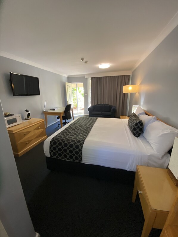 A hotel room with a bed, a desk, a chair, a television, and a window with curtains.
