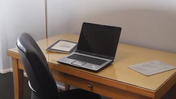 Un bureau en bois avec un ordinateur portable, une tablette et une lampe.
