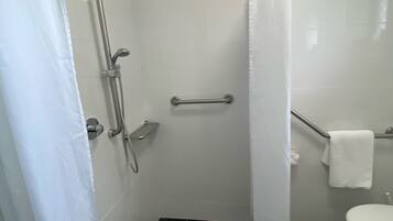 A bathroom with a shower, toilet, and a towel rack.