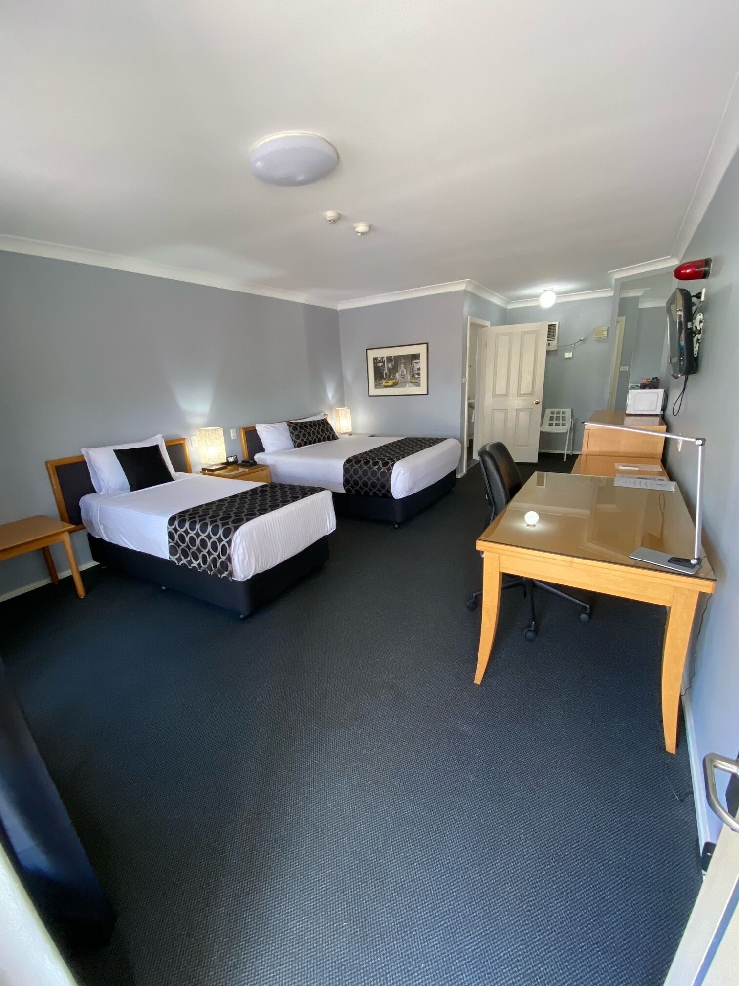A hotel room with two beds, a desk, a chair, a telephone, and a microwave.