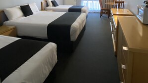 A hotel room with two beds, a desk, a chair, a television, and a door with a sign.