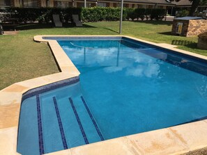 Una piscina al aire libre, sillones reclinables de piscina