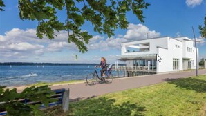 A modern building with a glass facade, a bike path, and a view of the water.