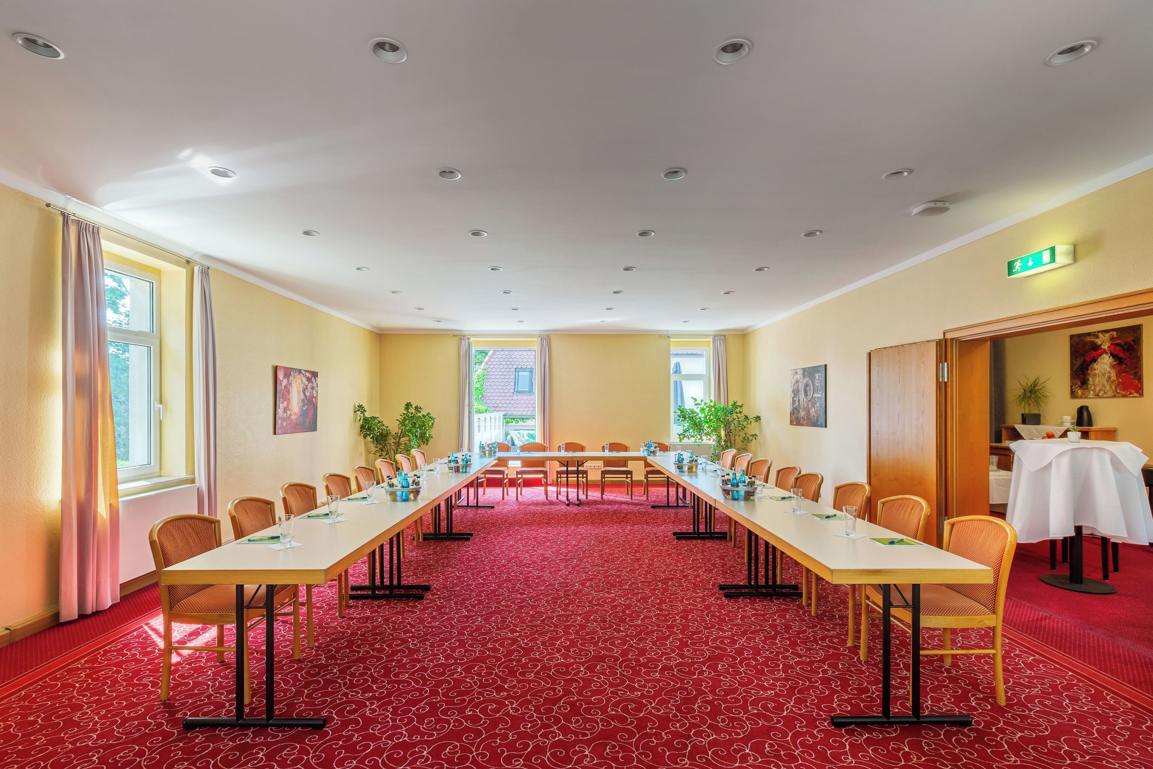 A conference room with a long table, chairs, and a red carpet.