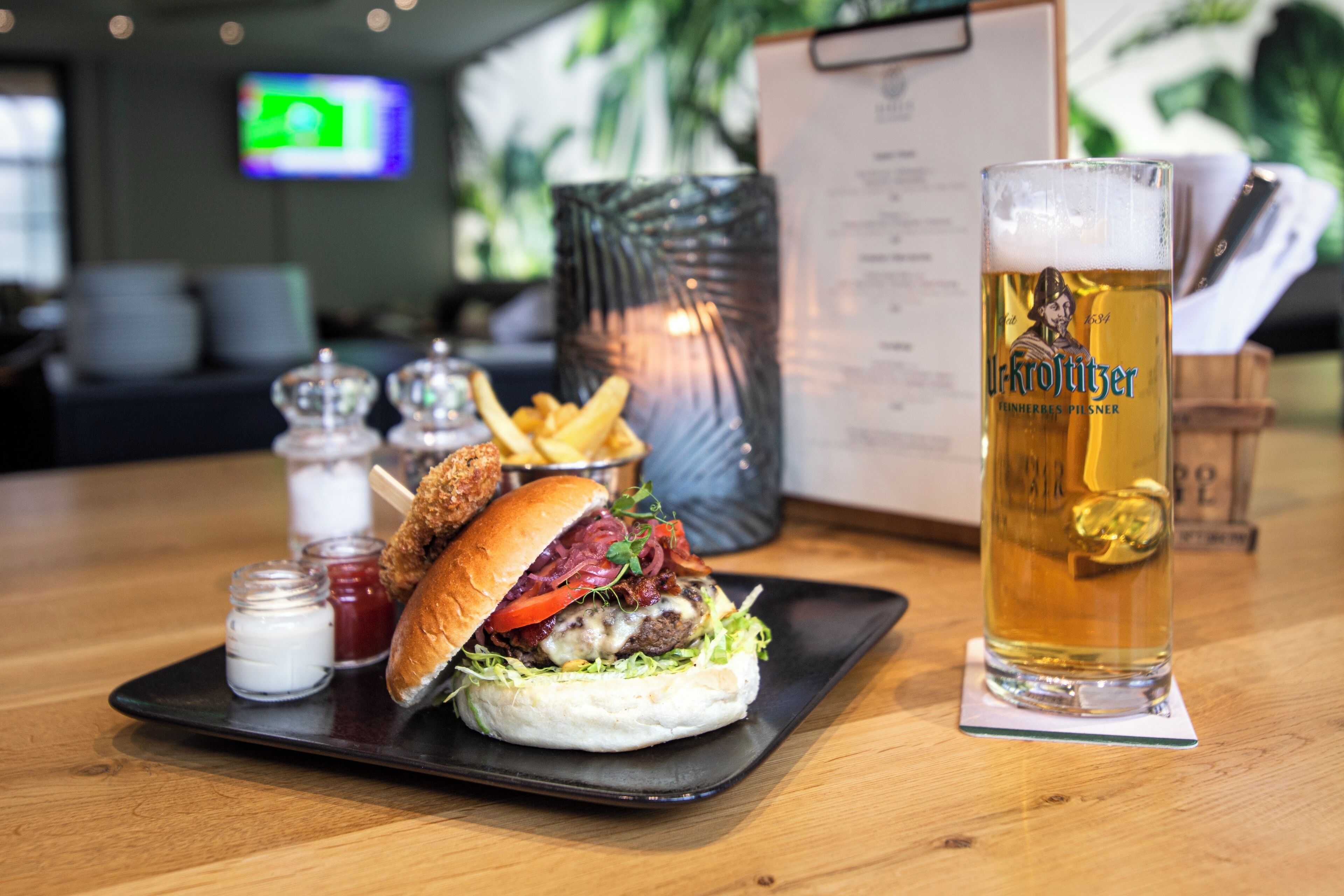 A burger with fries and a beer on a wooden table.