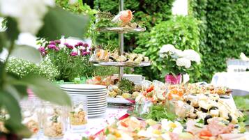 A multi-tiered appetizer stand with various food items and a floral arrangement in the background.