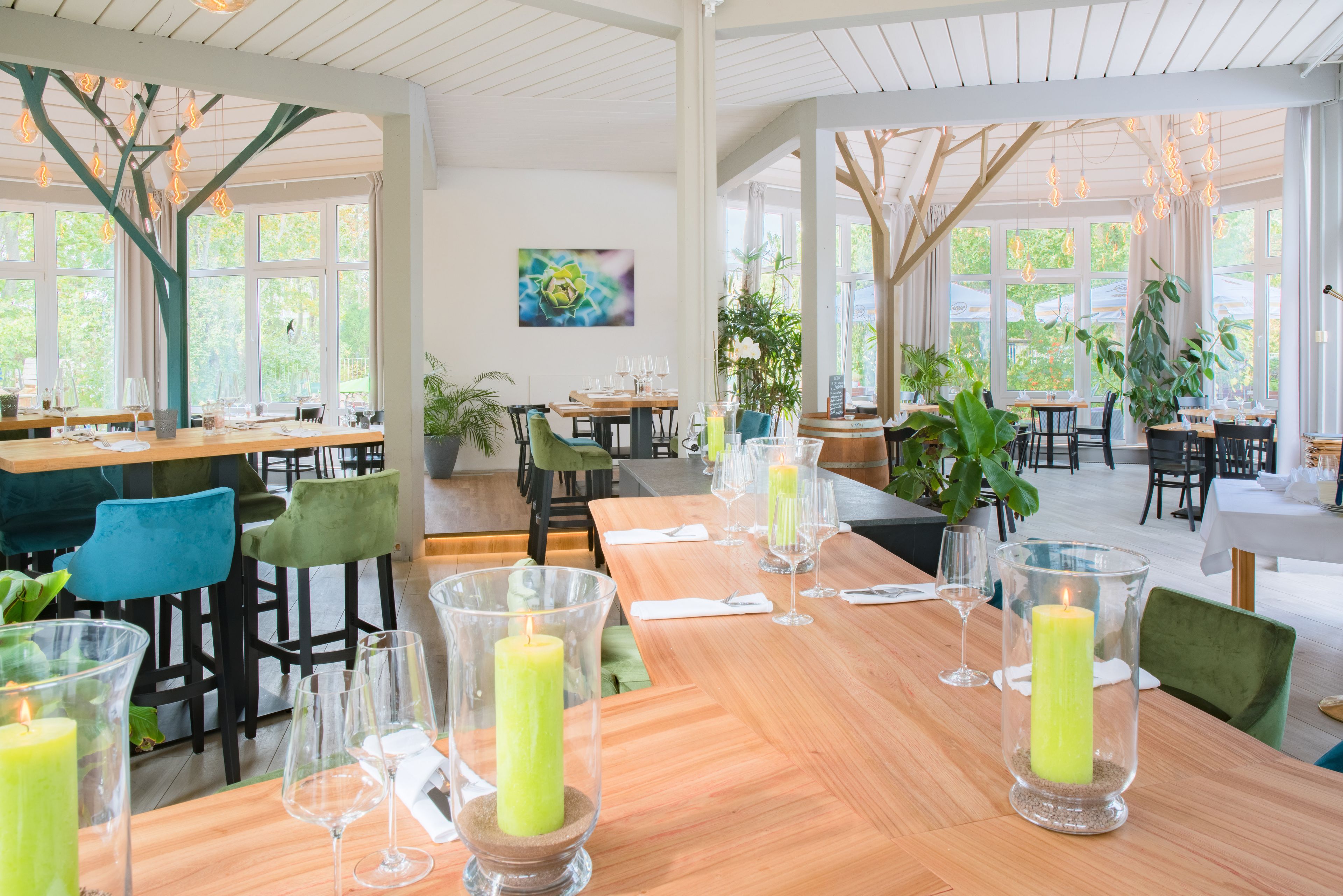 Un restaurante con mesas de madera, sillas verdes y velas.