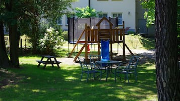 Guests can enjoy a safe play area with a slide and climbing elements, a picnic table, and comfortable seating on the well-maintained lawn.