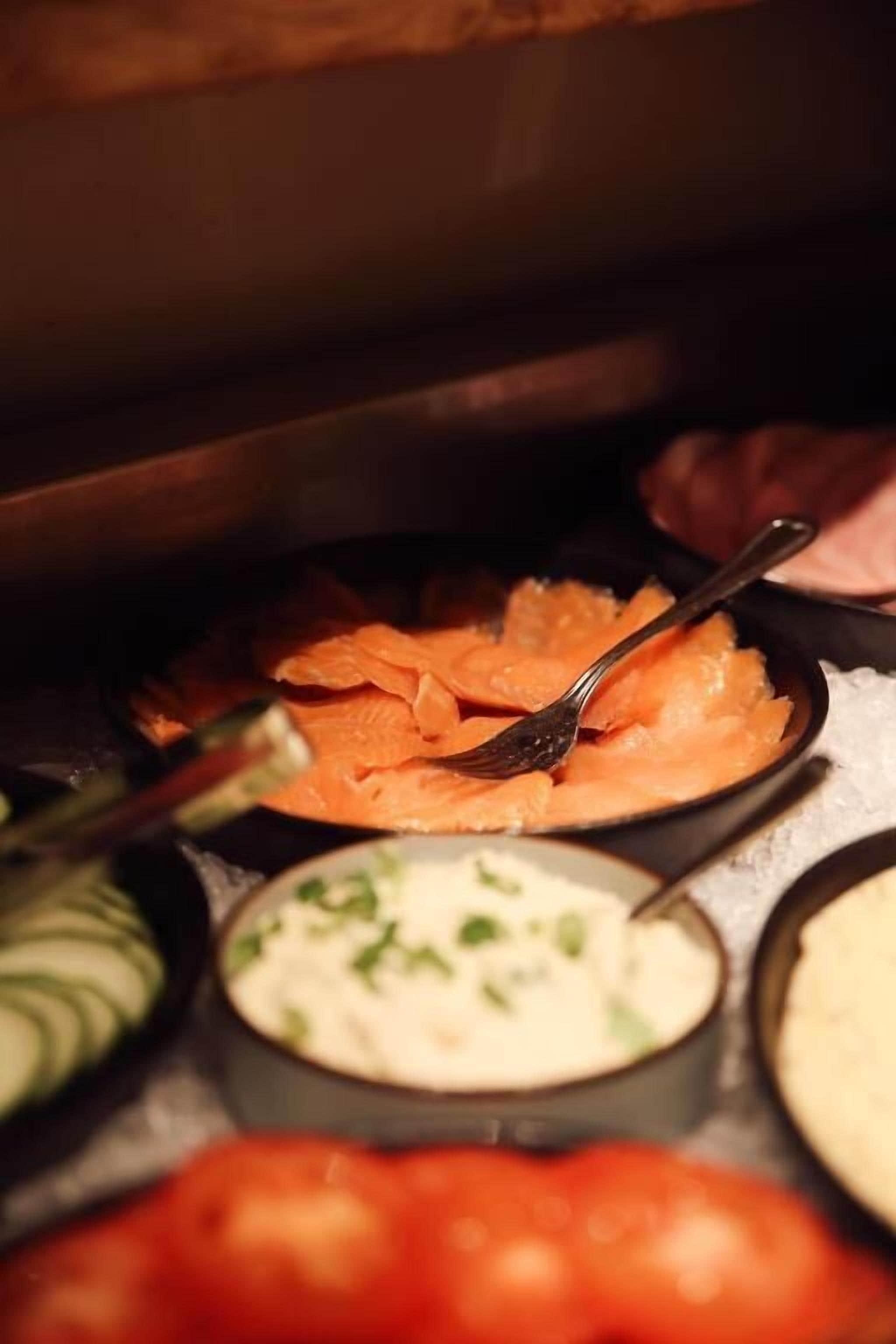 Un buffet proposant divers plats, notamment du saumon, une soupe crémeuse et un légume rouge.