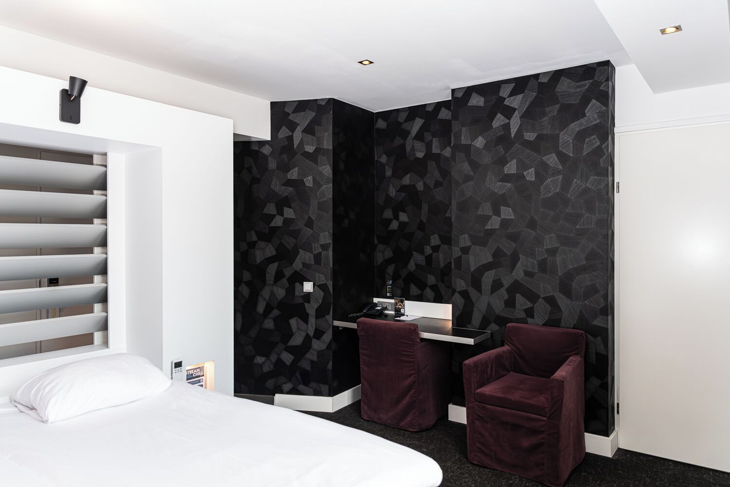 Una habitación de hotel moderna con cama, escritorio con silla y un amplio armario.