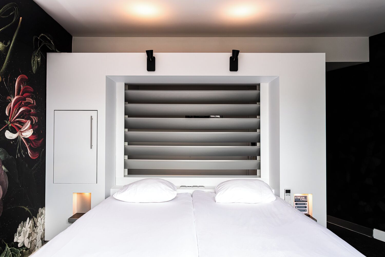 Een moderne slaapkamer met een groot bed, een inbouwbank en een wandlamp.