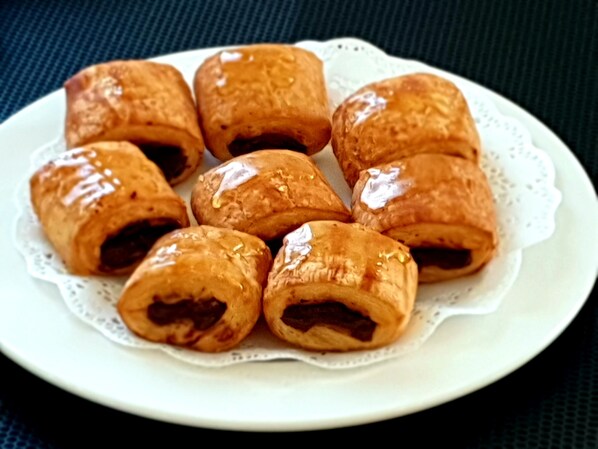 Un plato de pasteles dorados y brillantes, dispuestos sobre un plato blanco con un mantel de encaje.