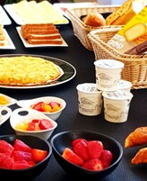 Uma mesa com diversos alimentos, incluindo pão, queijo, iogurte e morangos.