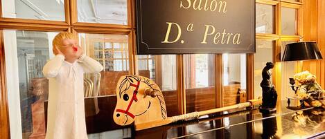 A polished black table with a sign reading "Salón D. Petra" and a wooden horse sculpture.