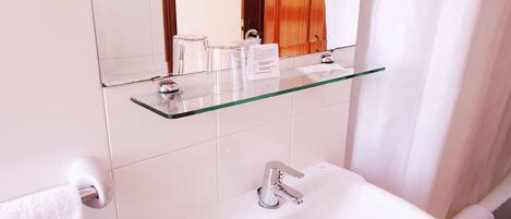 A bathroom with a glass shelf holding toiletries, a sink with a faucet, and a towel hanging on a rack.