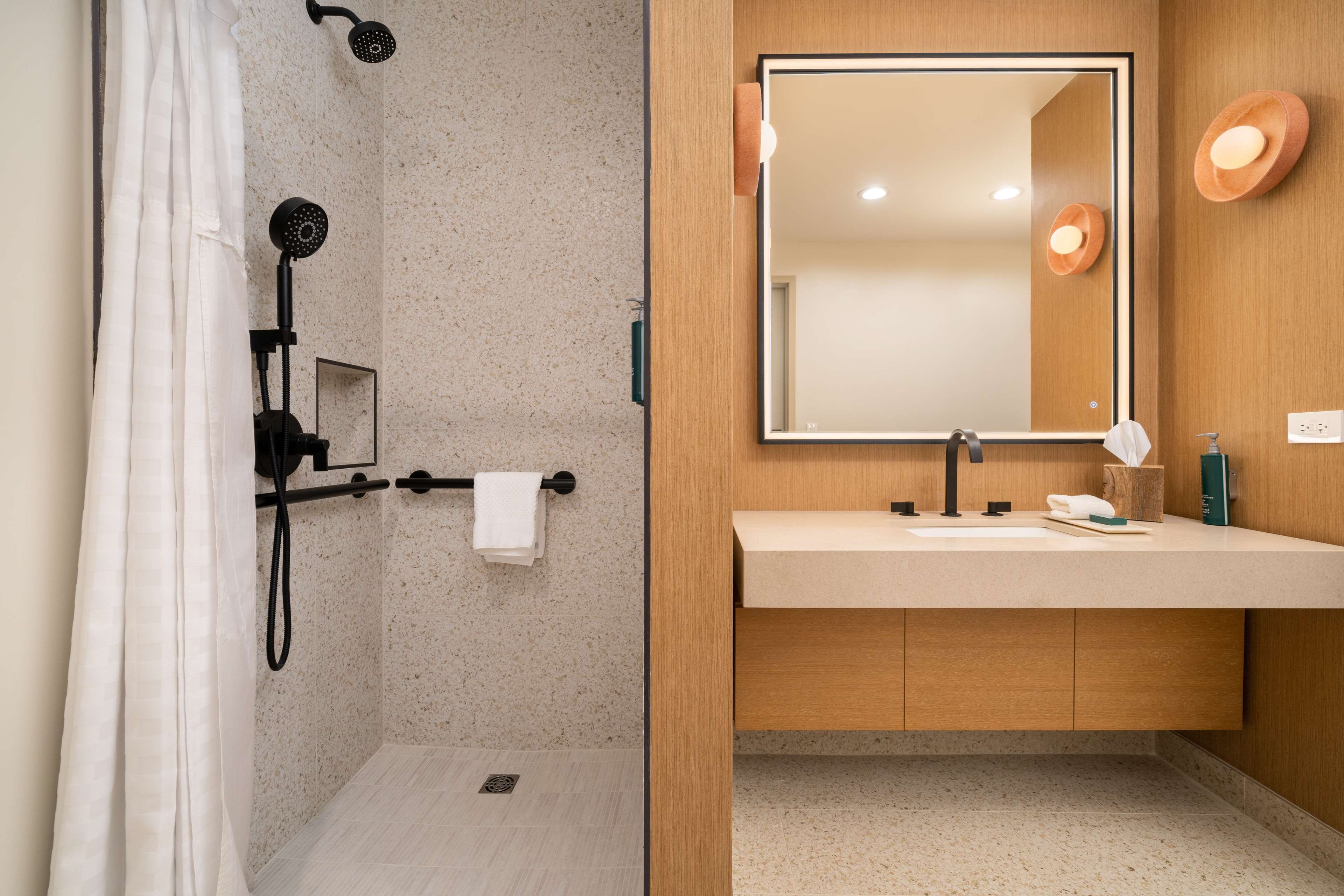 Un baño moderno con ducha, lavabo y espejo.