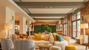 A modern lobby with a sofa set, armchairs, a small table, and a green wall with plants. - Hilton San Diego Gaslamp Quarter (San Diego)
