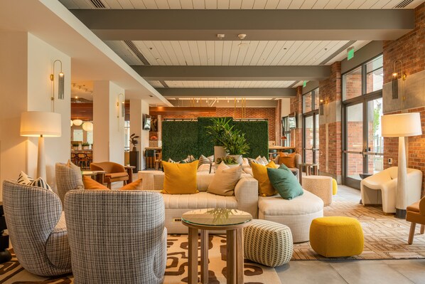 A modern lobby with a sofa set, armchairs, a small table, and a green wall with plants.