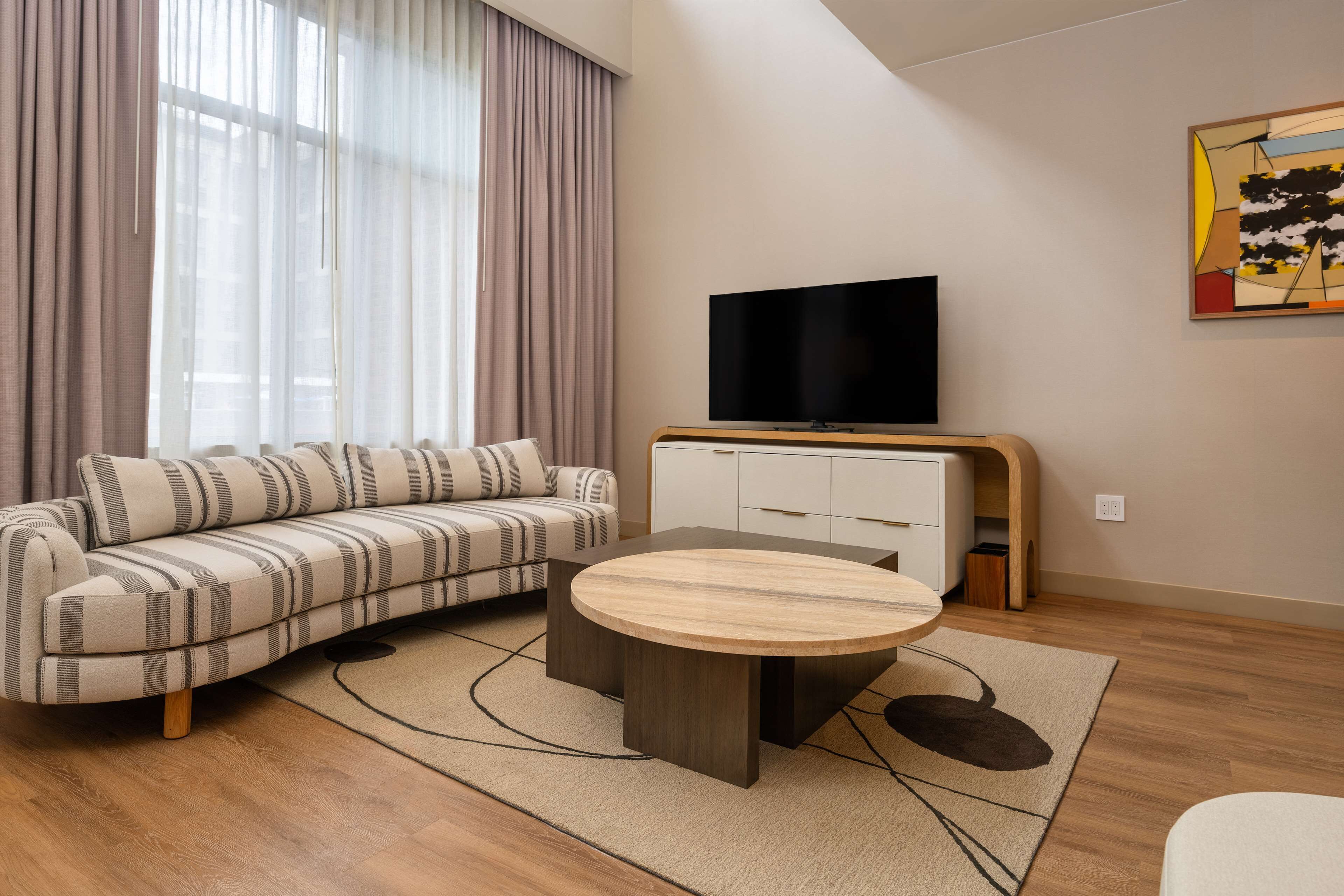 Una sala de estar moderna con un sofá, una mesa de centro, un televisor y un cuadro en la pared.