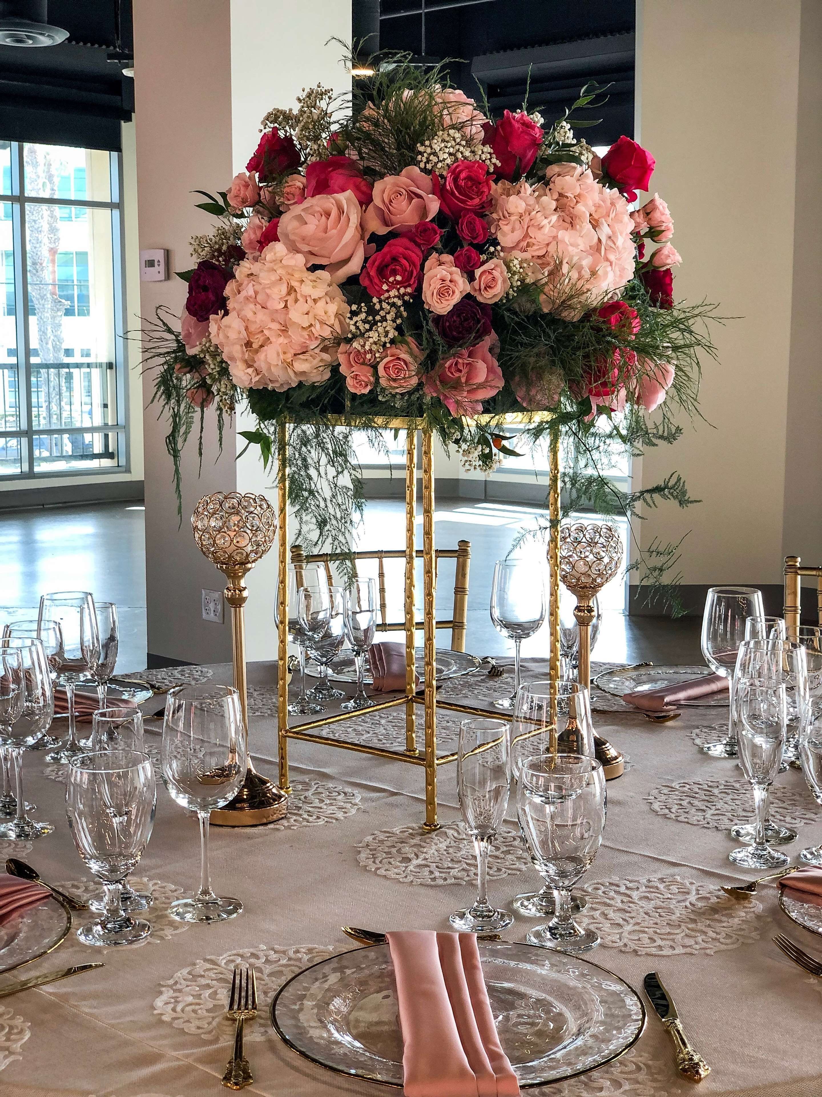 A table set for a formal event with a floral centerpiece, gold tableware, and clear glassware.