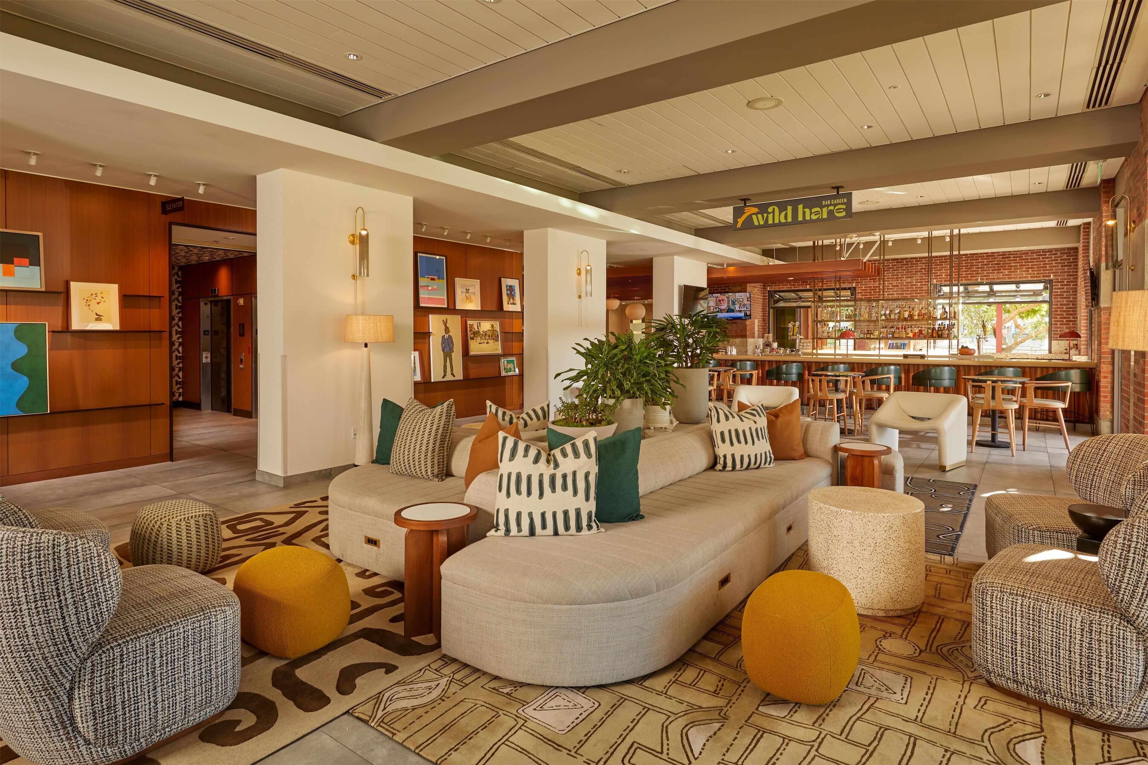 A modern hotel lobby with a curved sofa, seating area, and a bar.