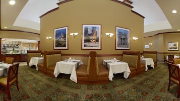 A restaurant with booth seating, tables, and framed pictures on the wall.