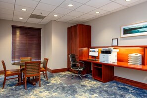 A conference room with a wooden desk, a computer, and a printer. There is a window with blinds, a chair, and a table with chairs. - Hilton Garden Inn Milwaukee Northwest Conference Center (Milwaukee)