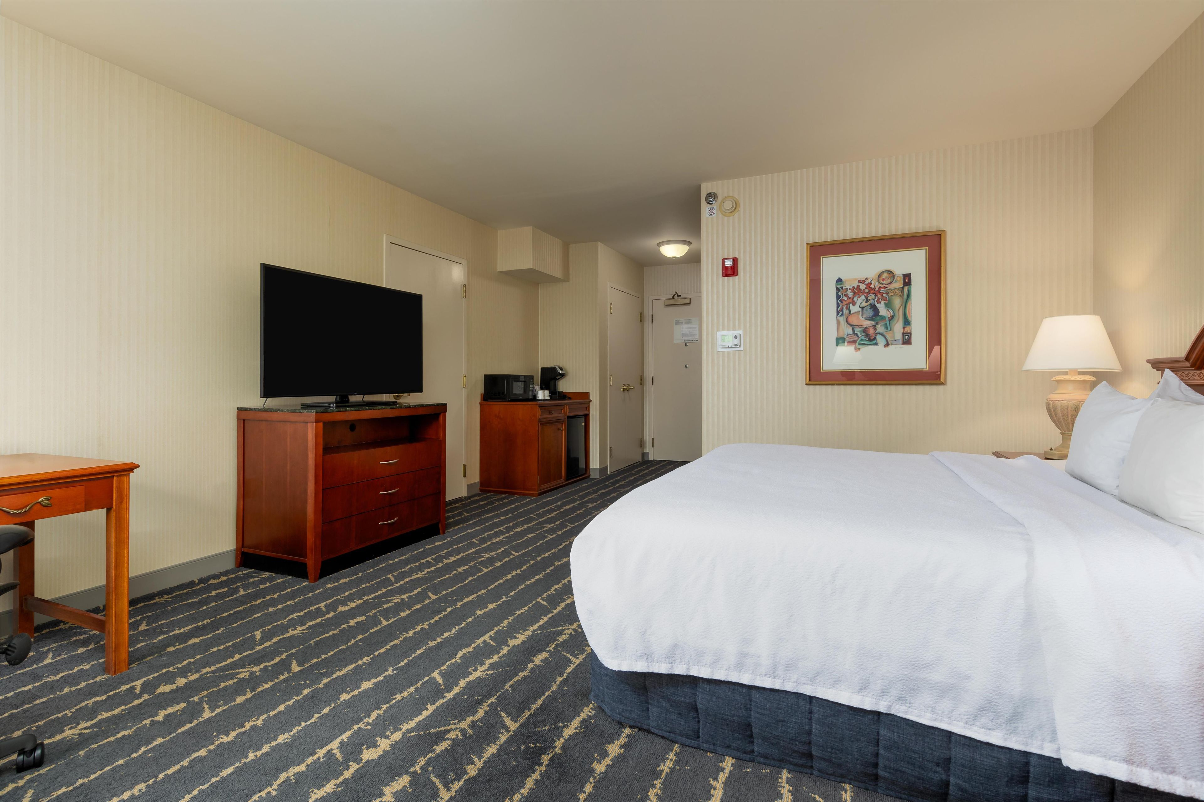Una habitación de hotel con cama, televisor, escritorio y cómoda.
