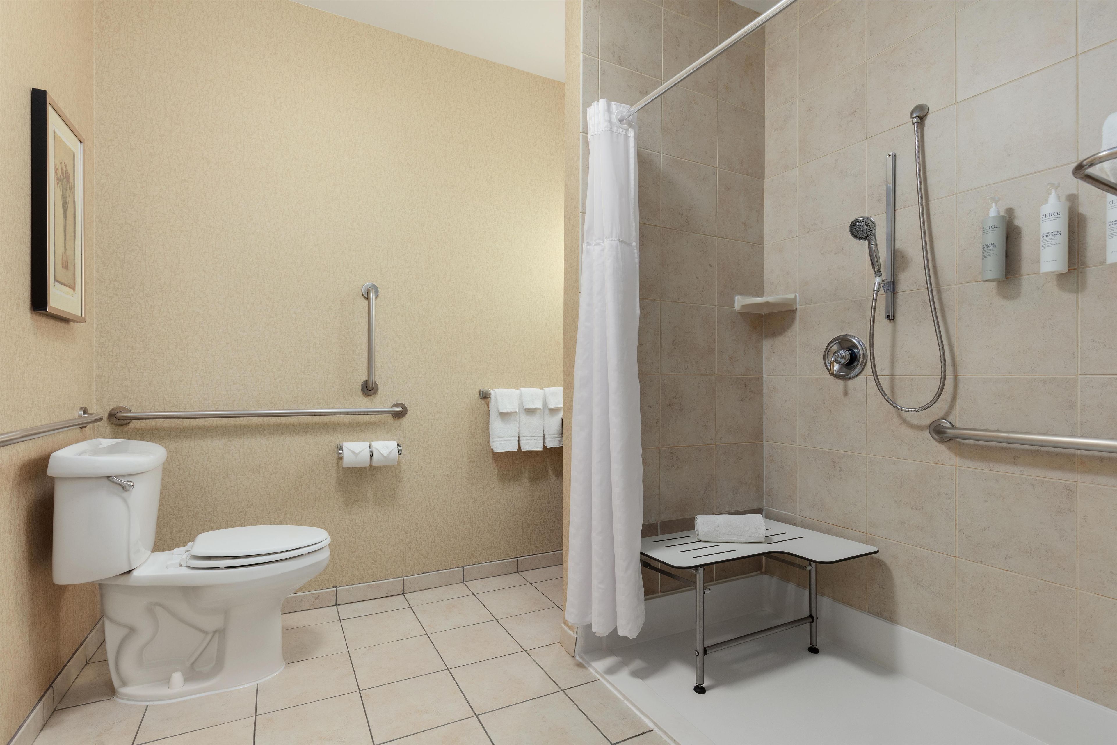 A bathroom with a toilet, shower, and grab bars.