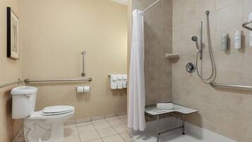 A bathroom with a toilet, shower, and grab bars.