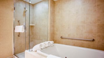 A bathroom with a bathtub, a glass shower enclosure, and a handrail.