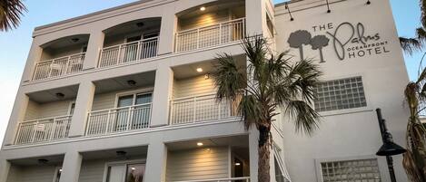 A multi-story hotel with balconies, palm trees, and a sign for "The Palms Oceanfront Hotel".