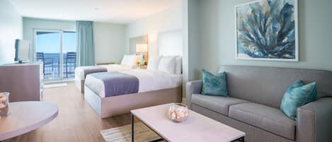 Una habitación de hotel moderna con una cama, un sofá, una mesita de centro y un cuadro en la pared.