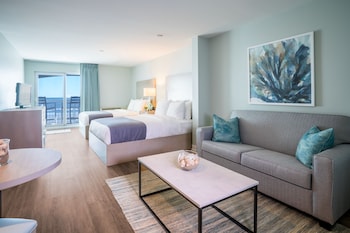 Relax in a serene space with a large bed, comfortable sofa, and a beautiful view of the outdoors. at The Palms Oceanfront Hotel