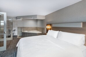 A hotel room with a large bed, a bathroom with a bathtub, and a wooden headboard. - Holiday Inn Express & Suites Wadsworth by IHG (Wadsworth)