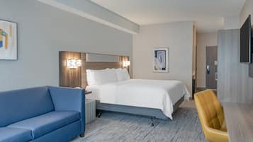 Et hotelværelse med en seng, en blå sofa, et træskrivebord og et fjernsyn.
