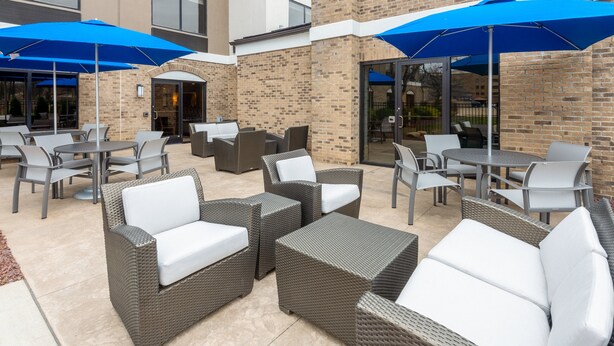 An outdoor patio area with wicker furniture and blue umbrellas. - Holiday Inn Express & Suites Wadsworth by IHG (Wadsworth)