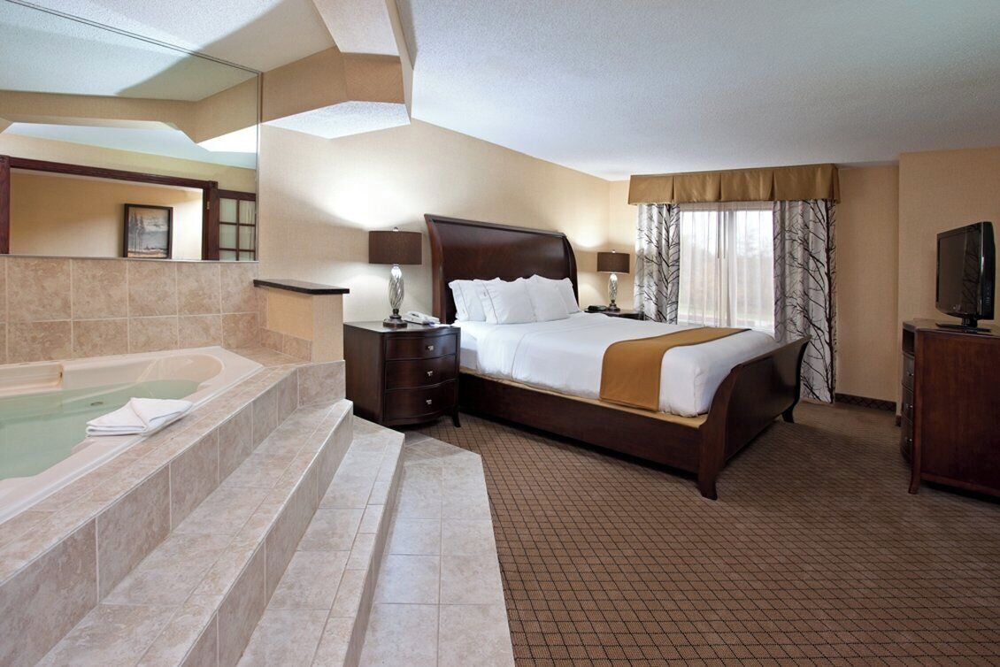 A hotel room with a large bed, a separate bathroom with a bathtub, and a television.