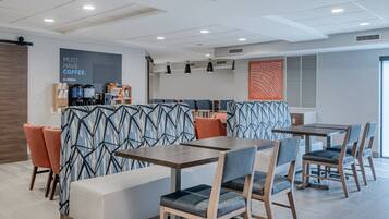 A modern cafe with seating arrangements, a coffee station, and a decorative wall.