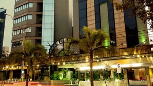 A modern hotel with a prominent glass facade, multiple floors, and a rooftop terrace. - Master Porto Alegre Hotel - Av Carlos Gomes, Proximo Consulado Americano (Porto Alegre)