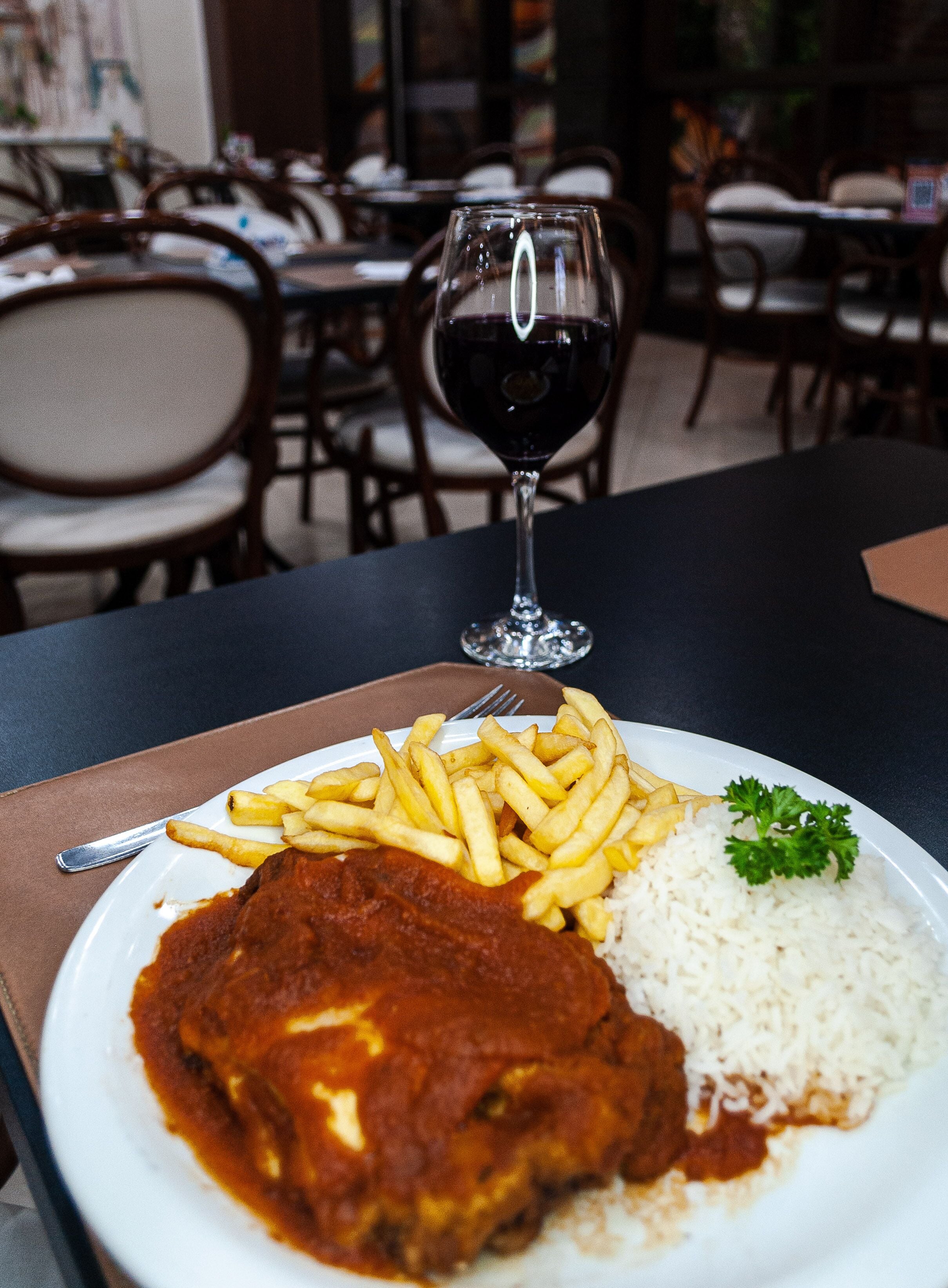 Um prato de comida com um copo de vinho tinto sobre uma mesa em um restaurante.