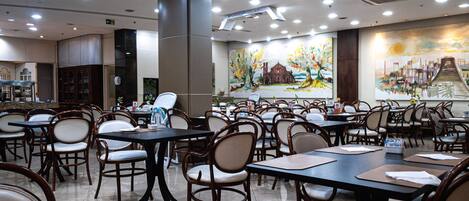 A spacious dining area with multiple tables and chairs, a large mural on the wall, and a modern ceiling design.