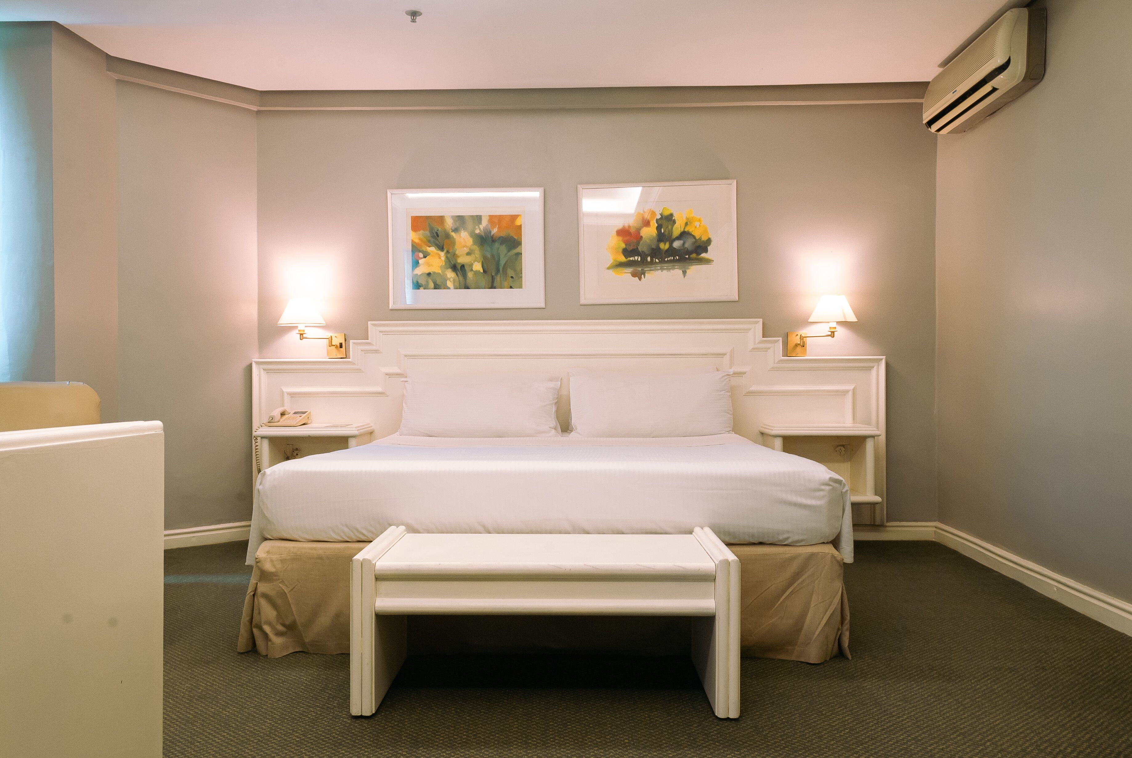 A neatly arranged hotel room with a large bed, bedside tables, and two wall-mounted lamps.