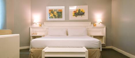 A neatly arranged hotel room with a large bed, bedside tables, and two wall-mounted lamps.