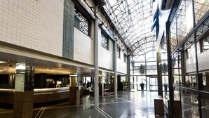 A spacious lobby with a high ceiling and a glass facade, featuring a reception area and seating. - Master Porto Alegre Hotel - Av Carlos Gomes, Proximo Consulado Americano (Porto Alegre)