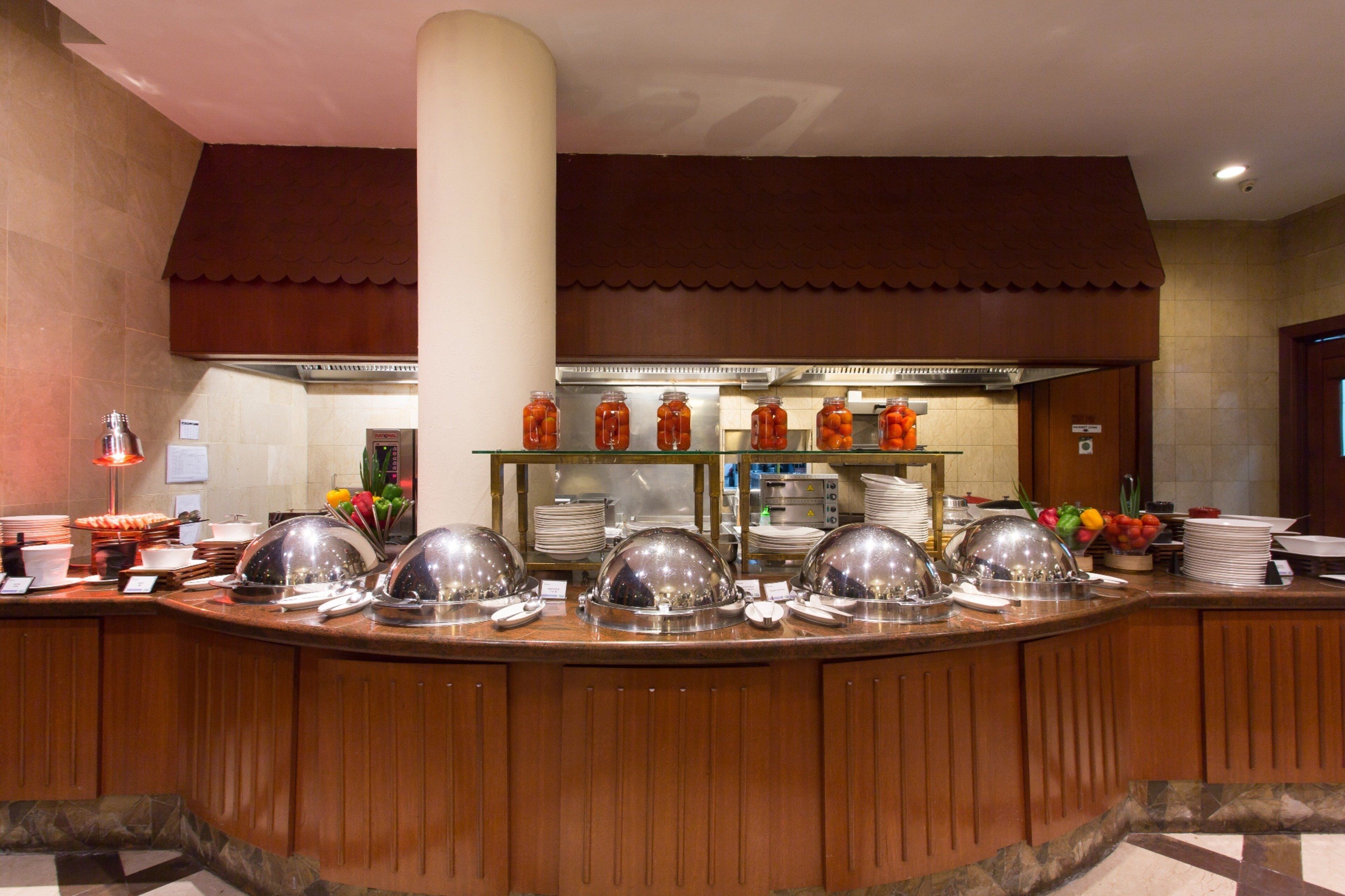 Montaje tipo bufé con varias estaciones de servicio, un pilar grande y una zona de cocina al fondo.