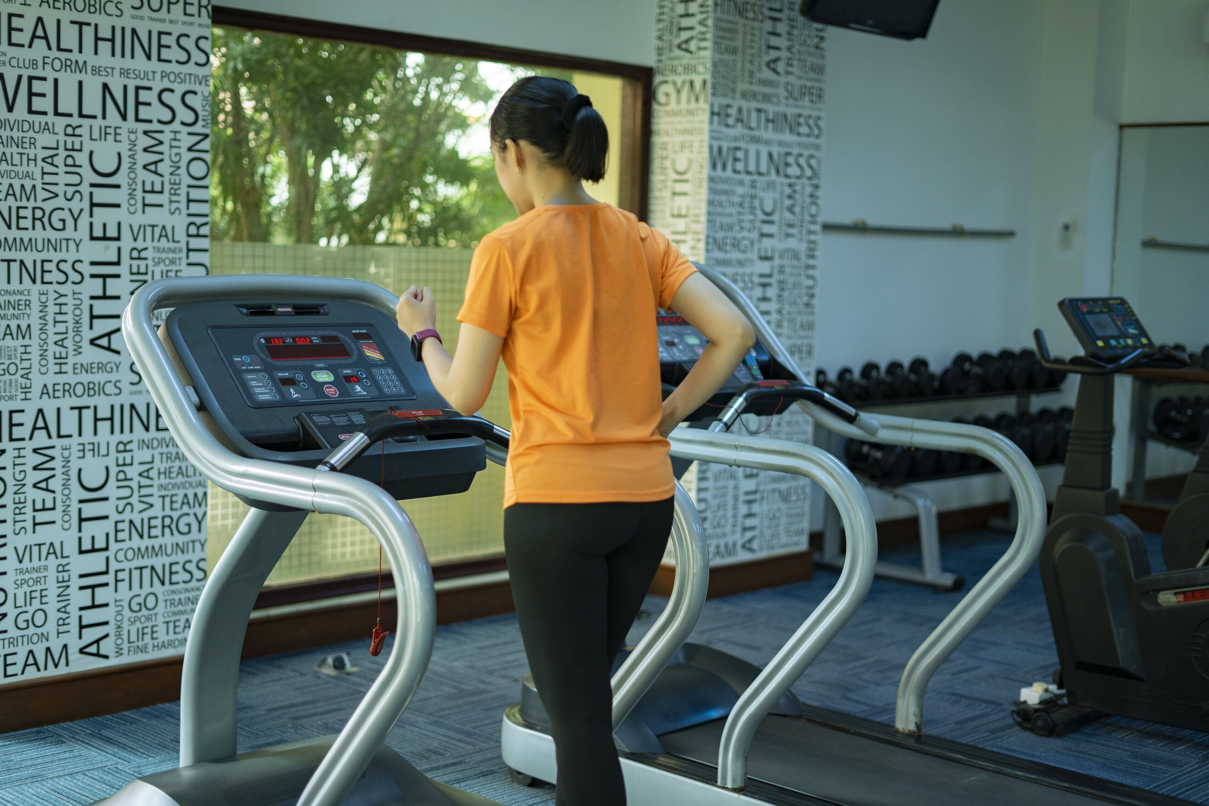 A woman using a treadmill in a gym with motivational words on the walls.
