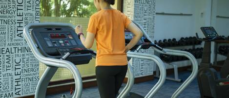 A woman using a treadmill in a gym with motivational words on the walls.