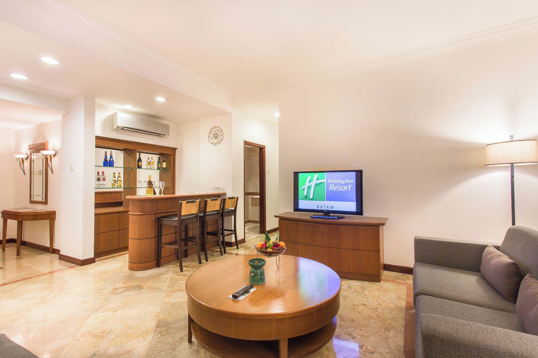Une chambre d’hôtel comprenant un coin bar, une télévision, une table basse ronde et un canapé.
