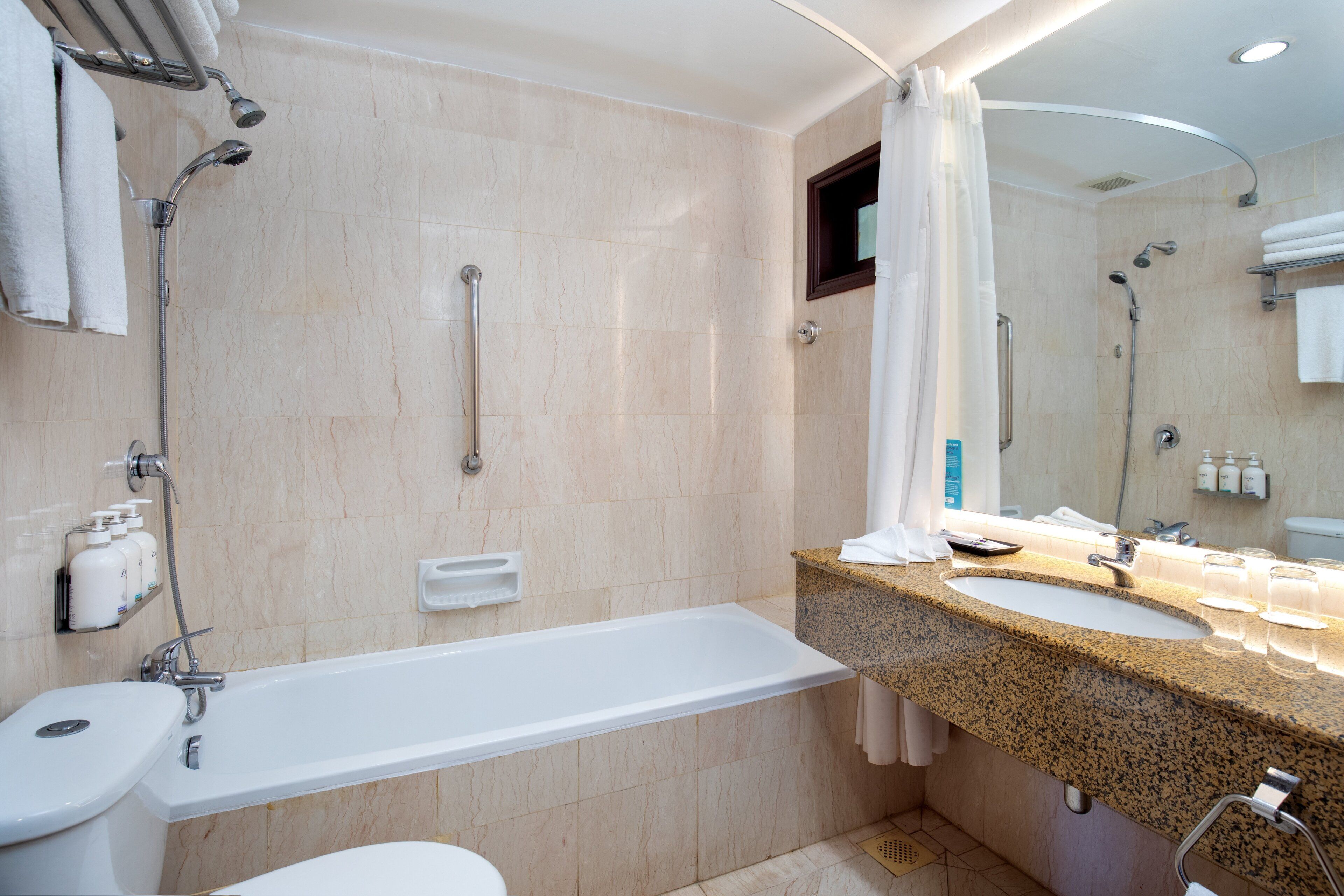 A modern bathroom with a bathtub, two sinks, a shower, and a toilet.